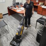 A trained cleaning professional vacuuming an office carpet, representing reliable professional home cleaning services and the best janitorial cleaning service.