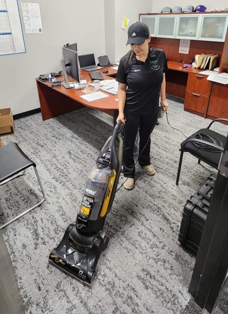 A trained cleaning professional vacuuming an office carpet, representing reliable professional home cleaning services and the best janitorial cleaning service.
